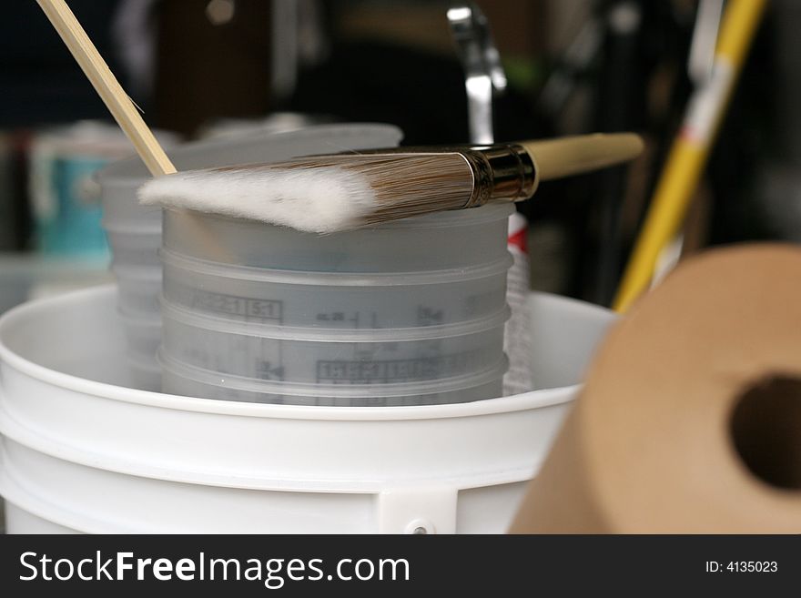 Paint brush with stir stick on bucket