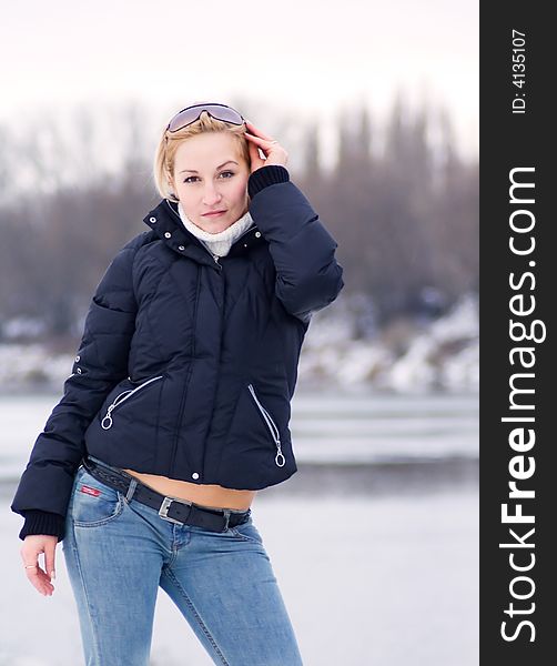 Beautiful blonde woman against a background of frozen river, forest and sky