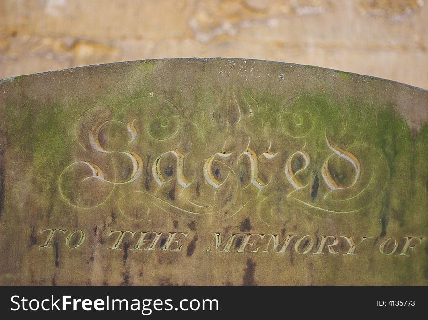 Grave stone with the word sacred,  lot of stone texture visible.