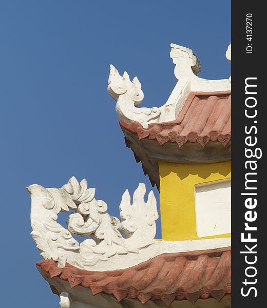 Detail of ancient, yellow Asian building on a blue sky background. Detail of ancient, yellow Asian building on a blue sky background.