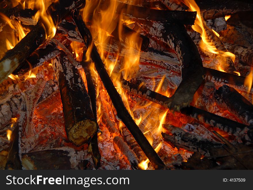 A close up view of hot coals in the middle of a burning wood fire. A close up view of hot coals in the middle of a burning wood fire.