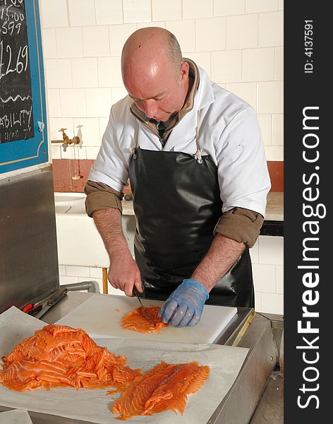 Fishmonger cutting slices of smoked salmon fresh from the smoke house. Fishmonger cutting slices of smoked salmon fresh from the smoke house