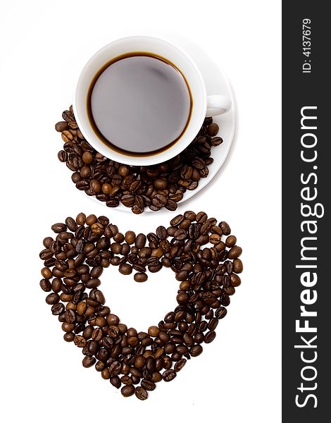 Heart made of coffeÑƒ beans and a cup of coffee isolated at the white background. Heart made of coffeÑƒ beans and a cup of coffee isolated at the white background