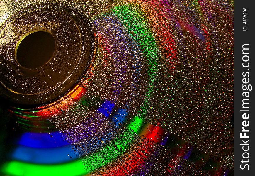 Full light spectrum on a cd quarter covered with water drops, black background. Full light spectrum on a cd quarter covered with water drops, black background