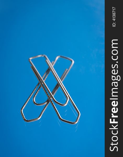Paper clip over a blue reflective background