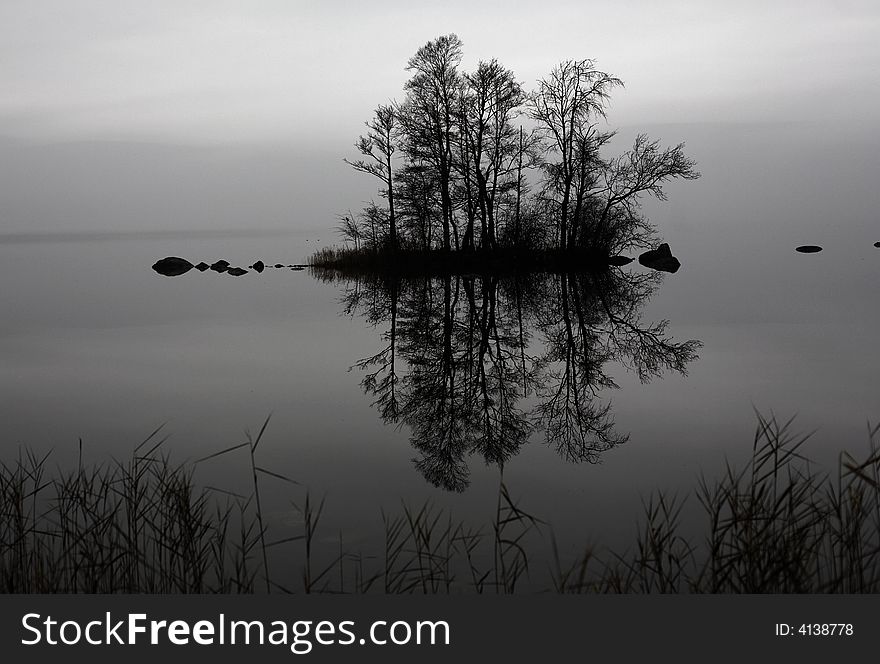 An island in the middle of a lake reflected in the calm water. An island in the middle of a lake reflected in the calm water.