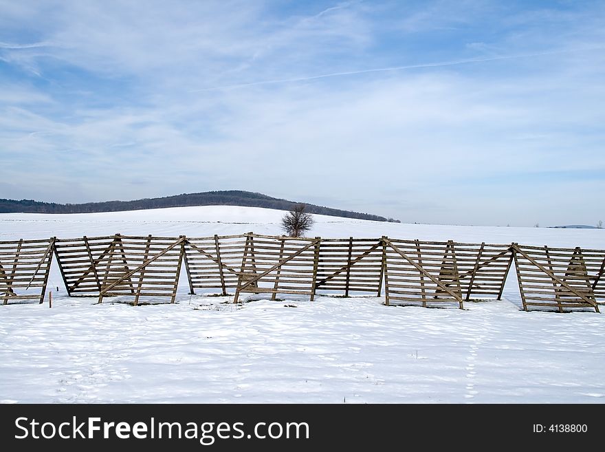 He is a snow-fence on a snowy tillage. He is a snow-fence on a snowy tillage.