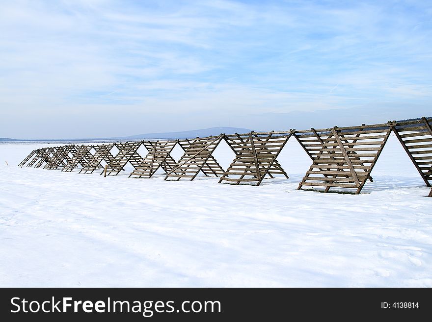 He is a snow-fence on a snowy tillage. He is a snow-fence on a snowy tillage.