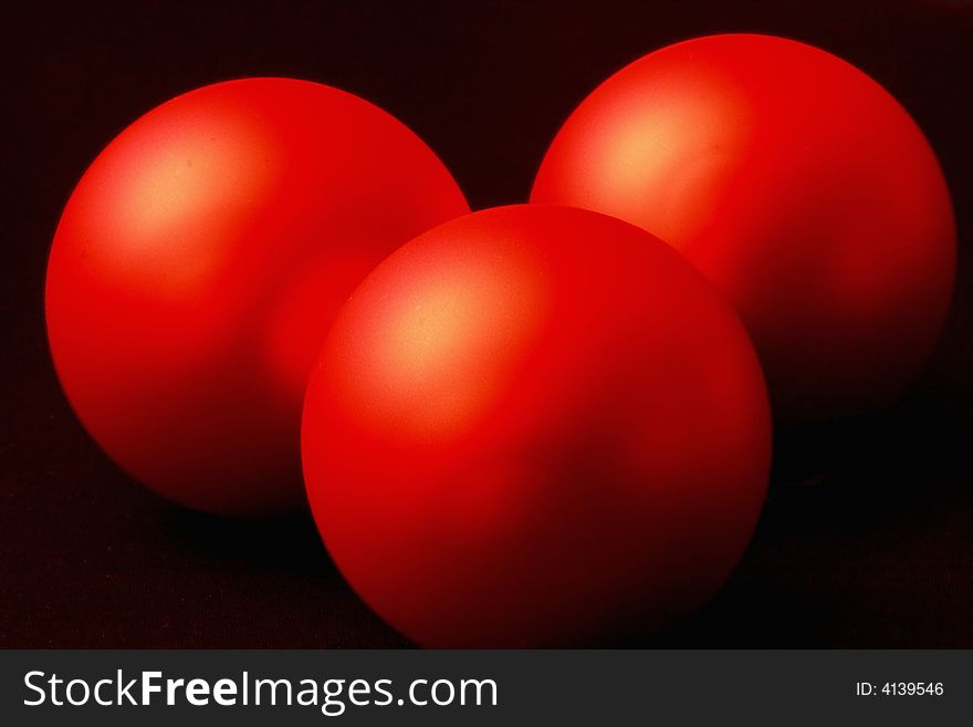 Close up of three red balls on black