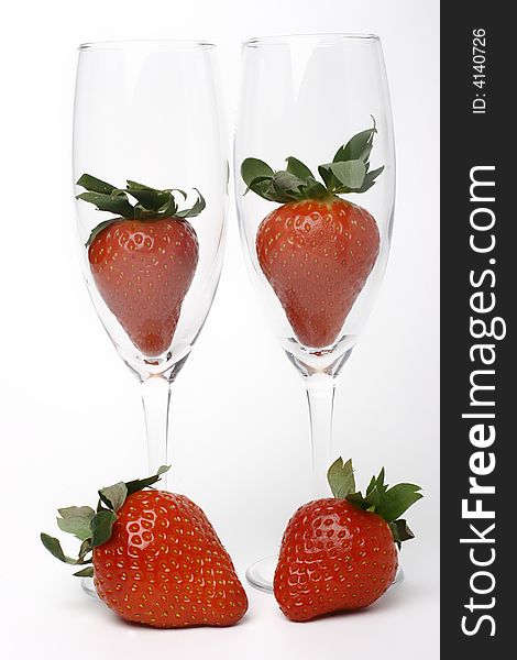 Four strawberries, two in glass, two beside glass. Four strawberries, two in glass, two beside glass