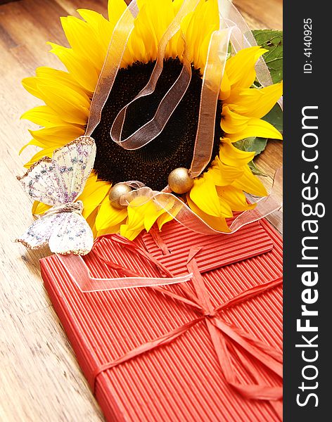 Sunflower, butterfly and a red box on a wooden table