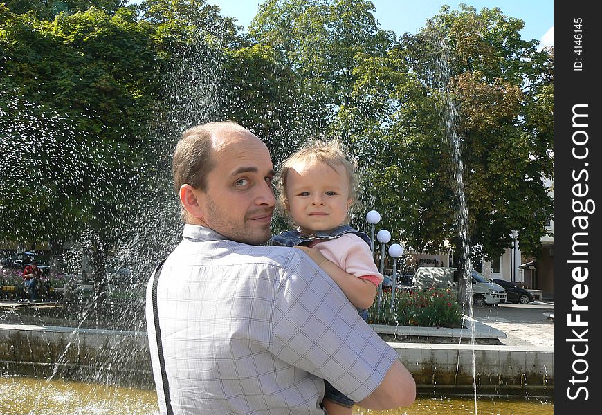 Happy daddy with baby girl near fountain