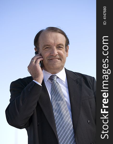 Older experienced businessman talking on his cellphone outside