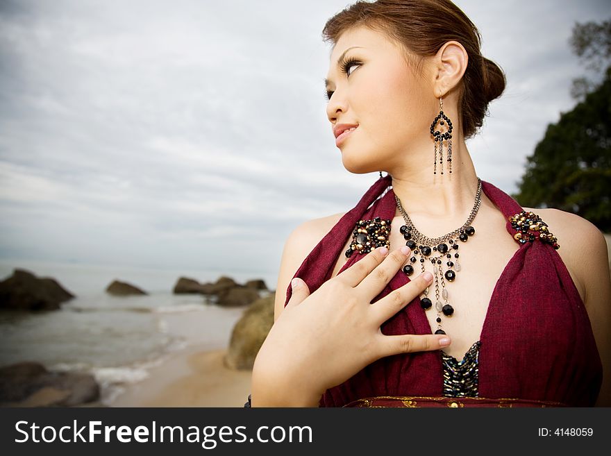 Young woman wearing accessories of ear rings and necklace by the sea side look out to the sea. Young woman wearing accessories of ear rings and necklace by the sea side look out to the sea