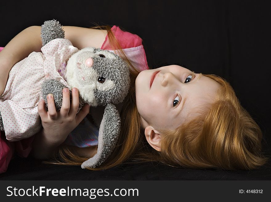 Small red-haired girl with her favorite stuffed animal - a rabbit. Small red-haired girl with her favorite stuffed animal - a rabbit.