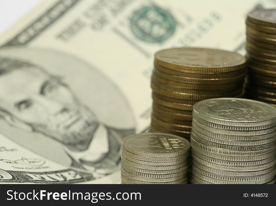 Close-up of multicolor coins stacks and five dollars bill as a background. Close-up of multicolor coins stacks and five dollars bill as a background