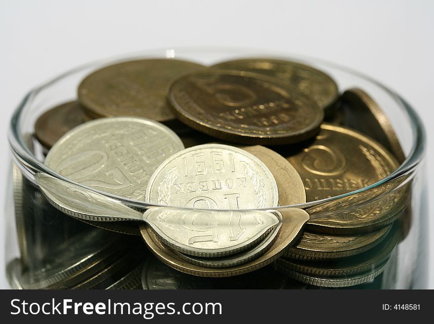 Close-up of multicolor coins in glass on the white background (isolated on white)