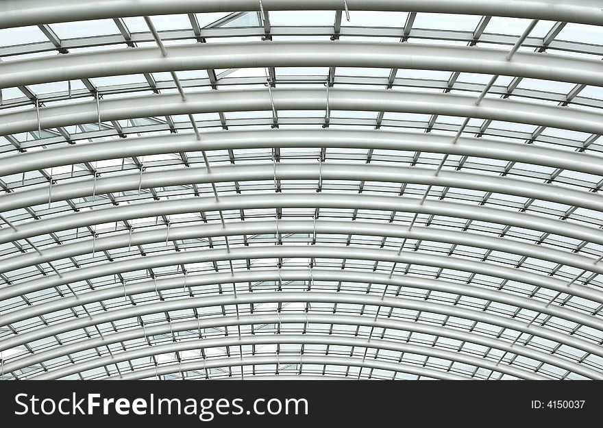 Curved reinforced steel roof joists in a conservatory with glass panes in between. Curved reinforced steel roof joists in a conservatory with glass panes in between.