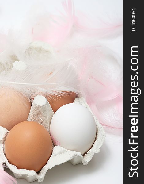 Natural eggs in a box with pink feathers on white background
