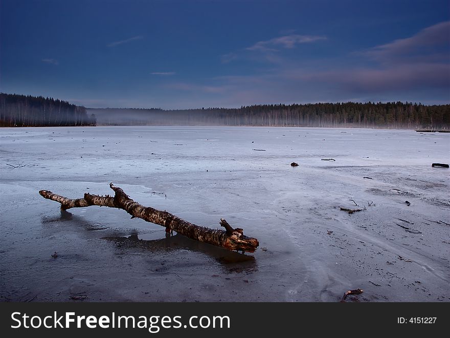 A tree trunk lying on a frozen lake. A tree trunk lying on a frozen lake
