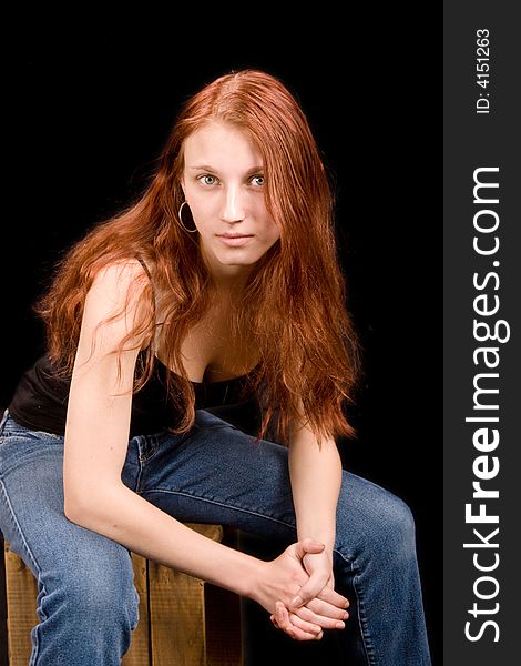 Beautiful thin redhead seated on wooden crate. Beautiful thin redhead seated on wooden crate
