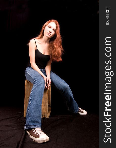 Beautiful thin redhead seated on wooden crate. Beautiful thin redhead seated on wooden crate