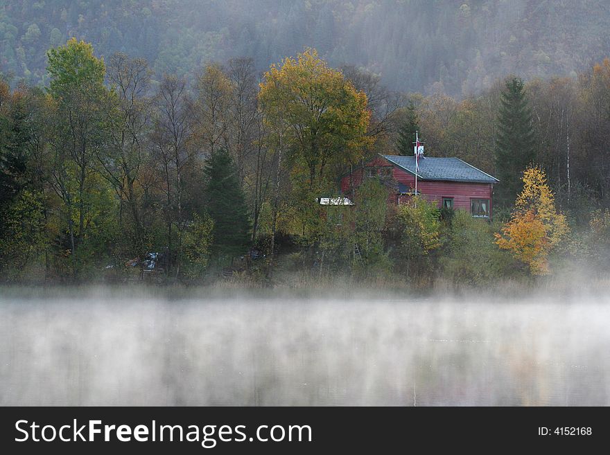 Small Red Wood house with myst over the water. Small Red Wood house with myst over the water