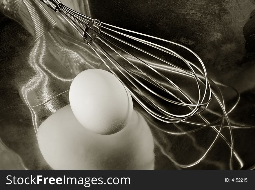 An egg reflecting in a Metal Dish with a whisk. An egg reflecting in a Metal Dish with a whisk.