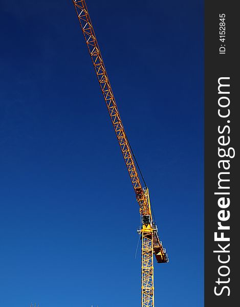 Yellow construction crane with clear blue sky as background. Yellow construction crane with clear blue sky as background