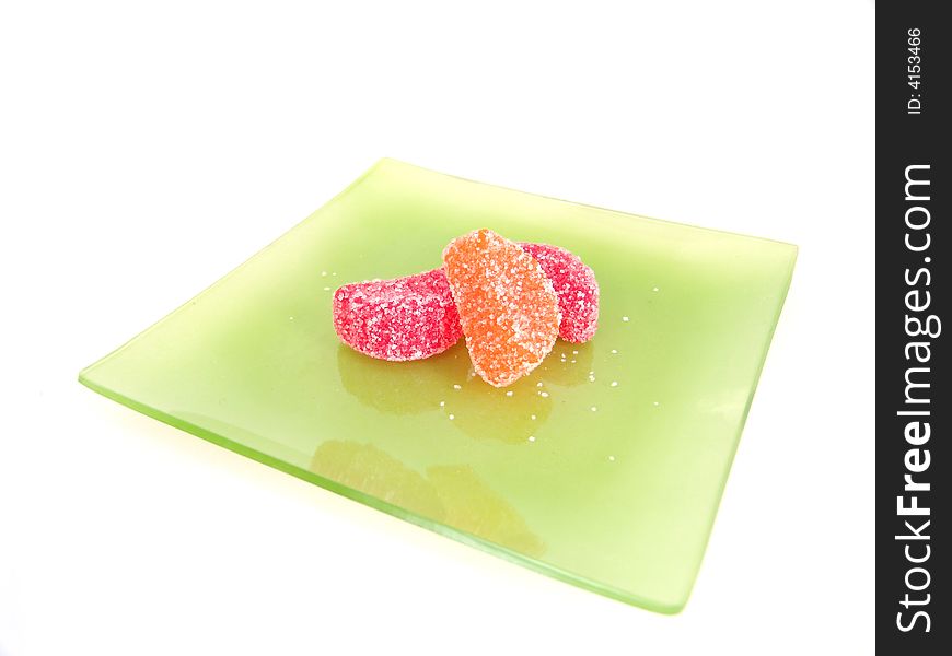 Three sugar coated candy fruit slice on green plate. Three sugar coated candy fruit slice on green plate