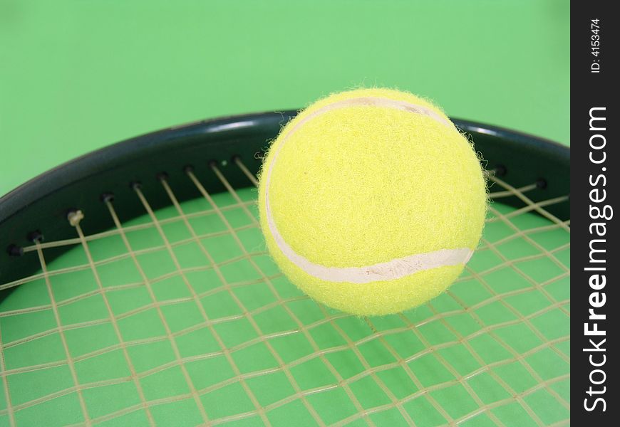 Yellow tennis ball on racket strings over green background. Yellow tennis ball on racket strings over green background