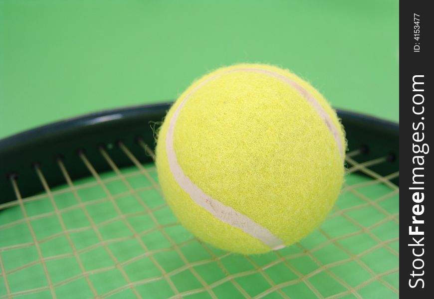 Yellow tennis ball on racket strings over green background. Yellow tennis ball on racket strings over green background