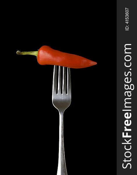 Red pepper on a silver for against a black background. Red pepper on a silver for against a black background