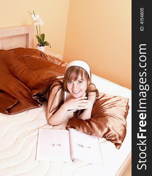 Young woman relaxing in the bed and reading newspaper. Young woman relaxing in the bed and reading newspaper.