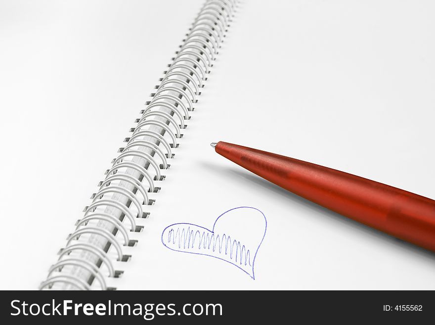 Open spiral notebook with red plastic pen and blue heart. Open spiral notebook with red plastic pen and blue heart.