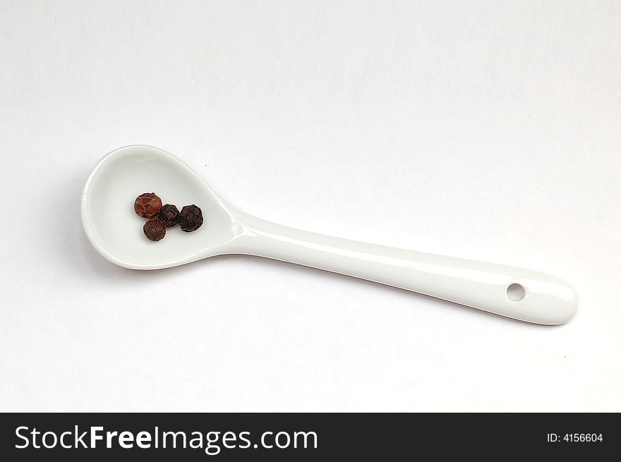 Some black pepper in spoon isolated