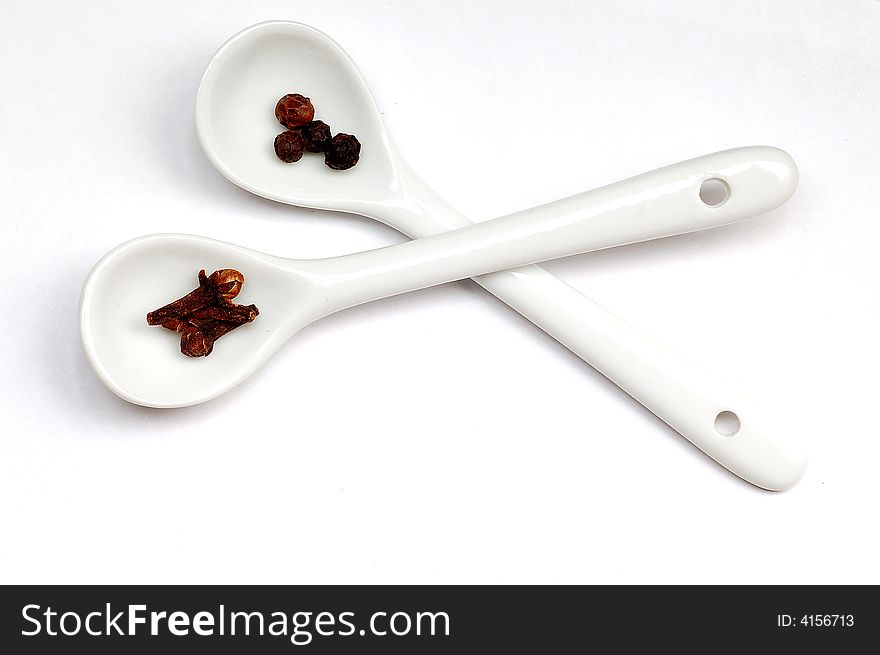 Black pepper&cloves in spoons isolated