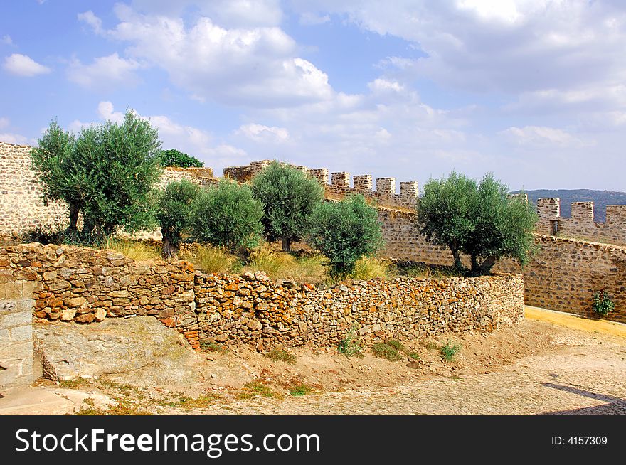 Portugal, area of Alentejo, Marvao: indoor view of the medieval defensive wall near the convention castle, blue sky and olive trees. Portugal, area of Alentejo, Marvao: indoor view of the medieval defensive wall near the convention castle, blue sky and olive trees