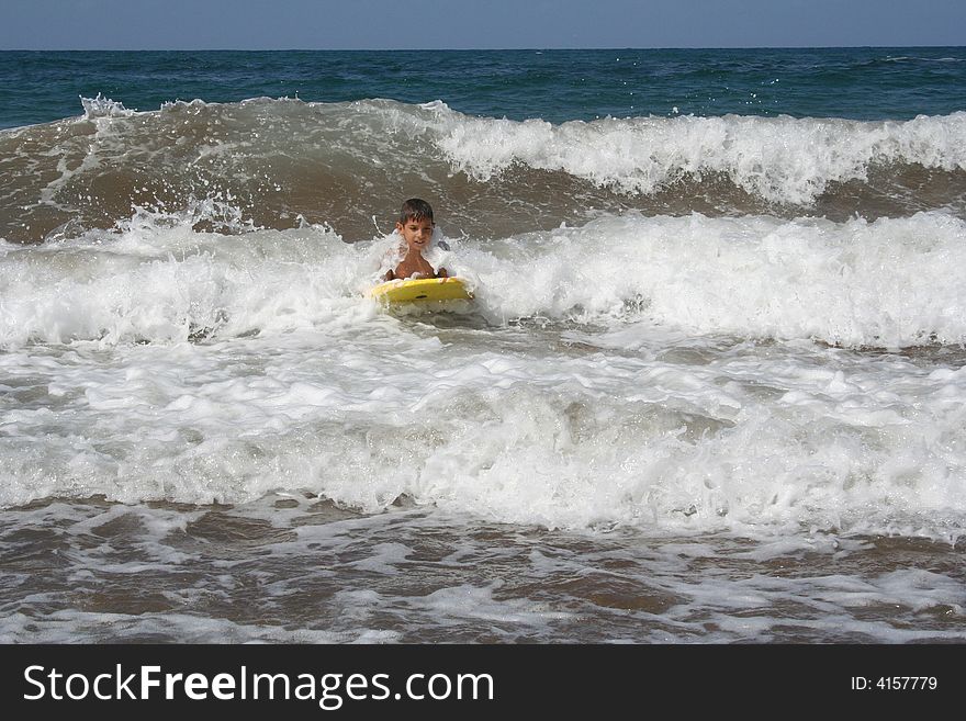 Little boy surfing some waves at the beach