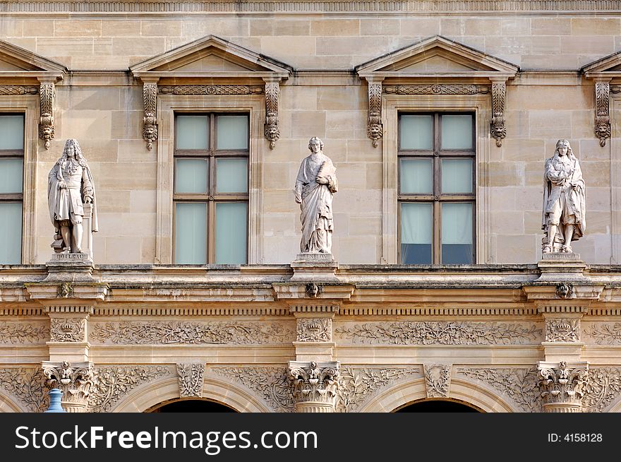 France, Paris: ancient famous monuments Louvre Palace; detail of the building, tree  stoned carved fronton and row of statues. France, Paris: ancient famous monuments Louvre Palace; detail of the building, tree  stoned carved fronton and row of statues