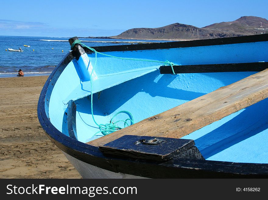 Blue fishing boat lying on the sand beach