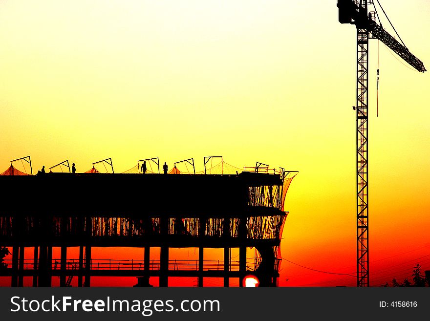 Workers on a construcion site at sunset. Workers on a construcion site at sunset