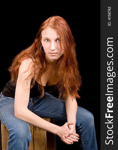 Beautiful redhead with blue eyes seated on wooden crate