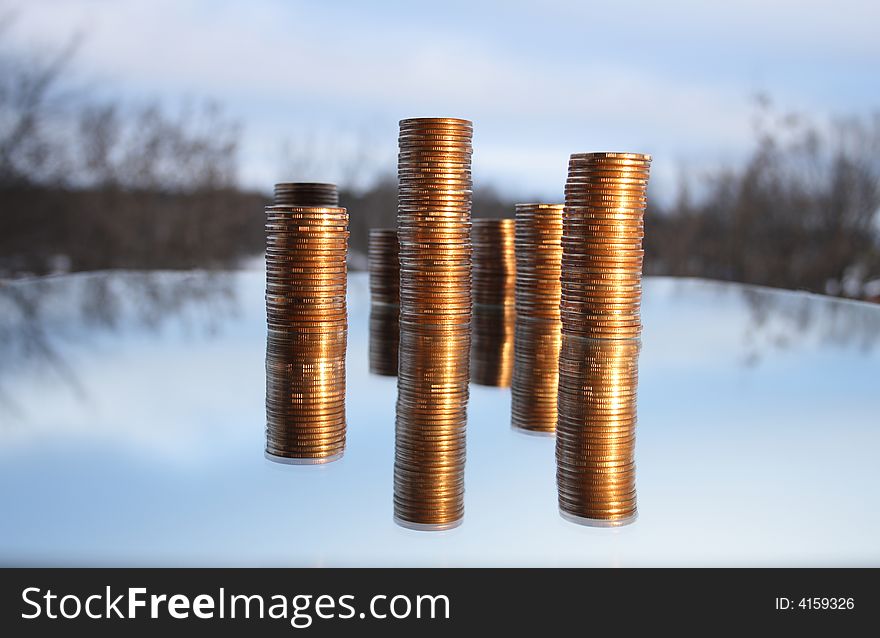 Towers made from coins with reverberation on winter background. Towers made from coins with reverberation on winter background