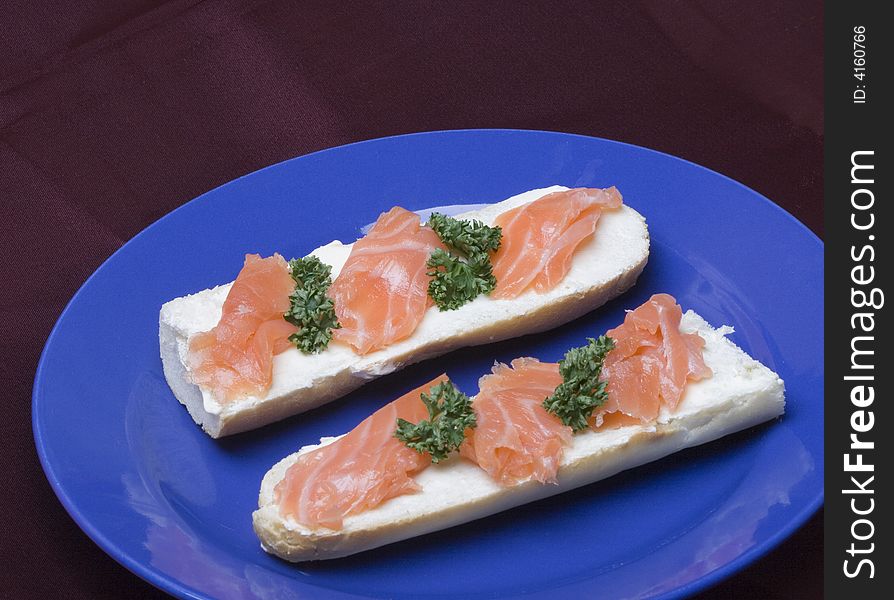 Smoked salmon on French bread on the blue plate