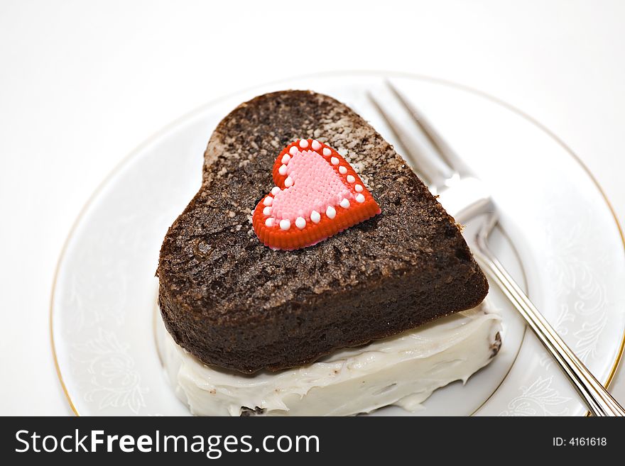 A heart shaped chocolate cake on plate with fork. A heart shaped chocolate cake on plate with fork.