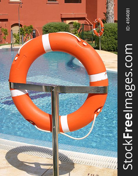 A life saving ring on a stand next to a swimming pool. A life saving ring on a stand next to a swimming pool