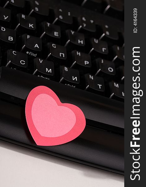 Paper pink heart lays on the computer keyboard. Paper pink heart lays on the computer keyboard