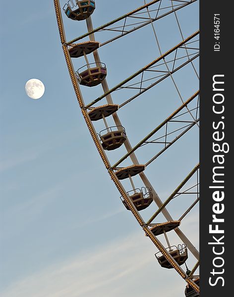 Ferris Wheel against cloudy blue sky (detail) with full moon. Ferris Wheel against cloudy blue sky (detail) with full moon