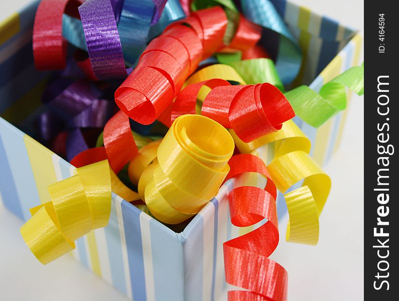 Curly ribbon in bright colours in a striped gift box. Curly ribbon in bright colours in a striped gift box.